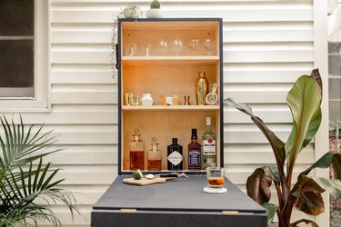 DIY outdoor Murphy bar attached to patio wall and stocked with liquor and bar supplies