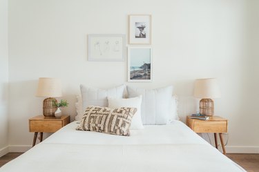 white bedroom with small gallery wall, calming colors, and tan wood nightstands