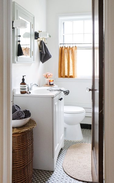 bathroom curtain idea with mostly white bathroom with a mustard-yellow linen cafe curtain in the window