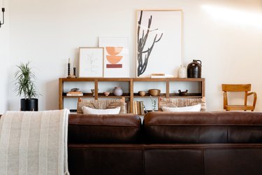 Brown leather sofa in living room paired with natural calming colors and woven wood chairs