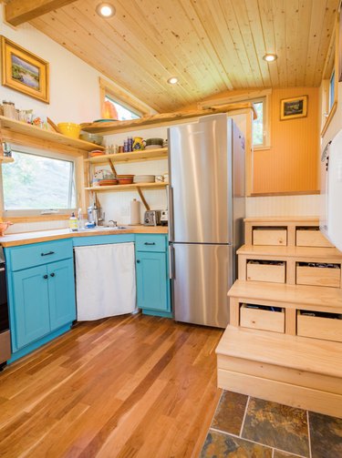 wood tiny house stairs in space with light wood floors, wood ceiling, recess lighting, and blue cabinets.