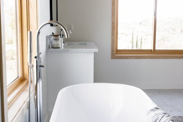sliding bathroom windows in bathroom with white standing tub and silver faucet
