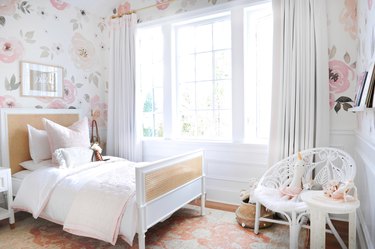 girls bedroom idea with floral patterned wallpaper and cane headboard