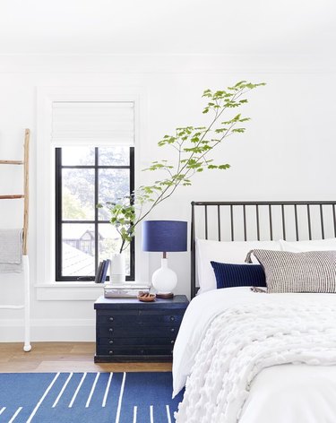 Light, bright rustic blue accents in bedroom with white bedding and large branch