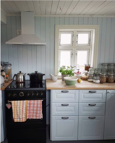 Pale rustic blue kitchen cabinets with shiplap walls