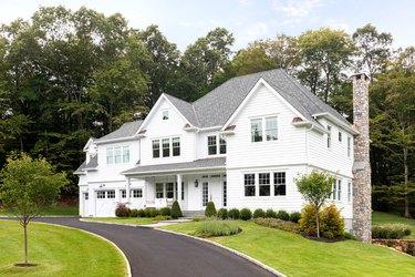 traditional home exterior idea with large white house surrounded by trees.