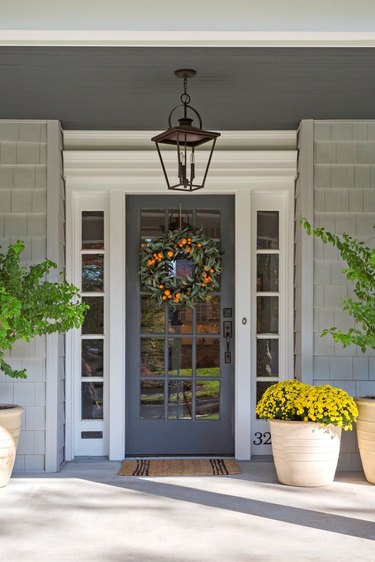 traditional home exterior idea of front porch with plants and a decorative wreath on the door