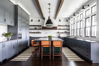 Grey-blue cabinets in a rustic blue kitchen with leather bar chairs