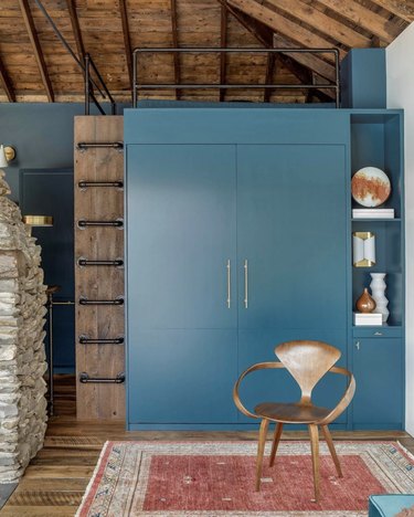 Rustic blue Murphy bed in a cabin with vintage red rug