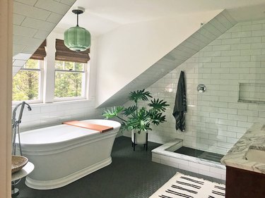 bathroom window with natural wood shades and arched shower with subway tile