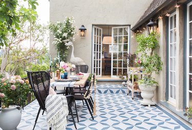 backyard patio with patterned tile and woven rattan chairs with open French doors