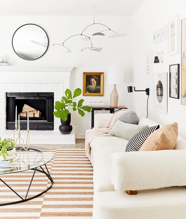 white living room with striped rug and traditional fireplace, white sofa, coffee table