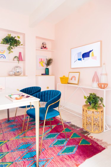 pastel pink home office with bright pink rug and blue velvet office chairs