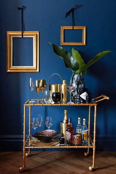 Pantone Color of the Year Classic Blue accent wall with brass picture frames and bar cart