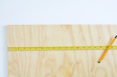 Measuring plywood with yellow tape measure