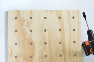Plywood pegboard with peg holes and drill
