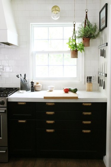 Traditional double-hung kitchen window in kitchen with black cabinets and white tile