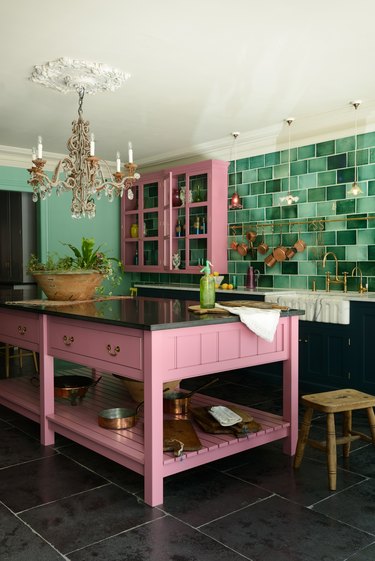 maximalist kitchen with green backsplash and pink cabinets and crystal chandelier