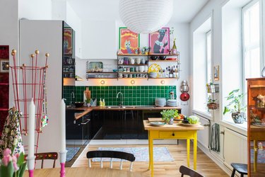 colorful maximalist kitchen with green tile backsplash and black cabinets