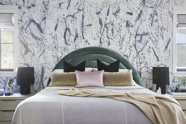 maximalist bedroom with patterned wallpaper and arched channel-tufted headboard
