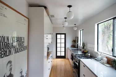 Simple metal kitchen windows in kitchen with white globe pendant lights and white cabinets