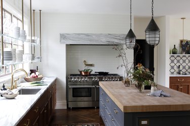 Open shelving in front of traditional kitchen windows in kitchen with dark island