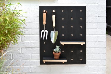 Painted wooden pegboard with garden tools