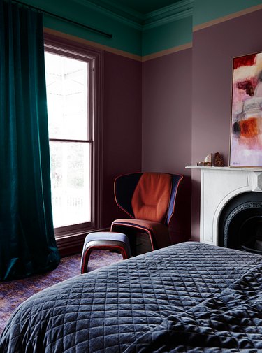 Plum and teal bedroom with navy blue bedspread and purple and red chair.