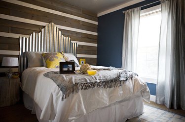 rustic glam bedroom with wooden feature wall, gold headboard, andrustic glam decor
