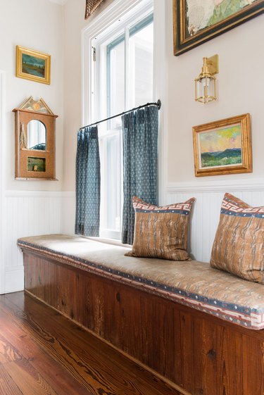 vintage window bench with curtains and wall art surrounding it
