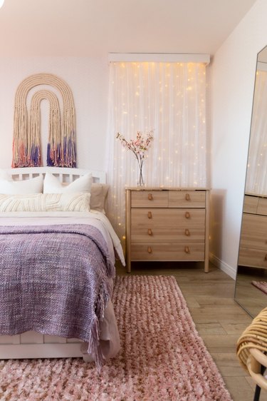 Pink and purple bedroom with fairy lights on wall and modern wall tapestry