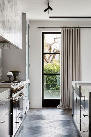 black windows in kitchen with gray window treatmeants and chevron floor