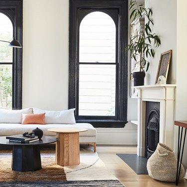 black windows in living room with black coffee table and white fireplace