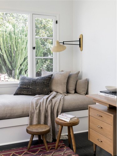 white room with gray window bench and two stools below it