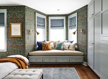 green wallpapered bedroom with bay window bench seating with pillows