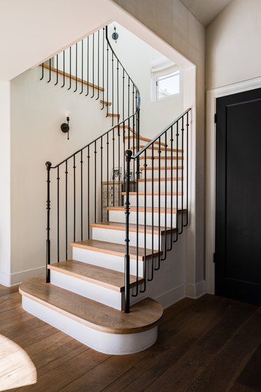 elongated balusters that attach to black stair railing with wood steps