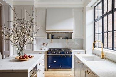 black windows in white kitchen with blue stove and white range hood