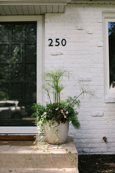 Traditional brick home painted white and featuring midcentury house numbers