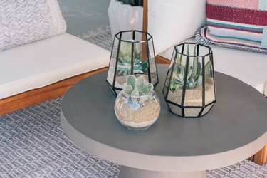 outdoor living area with three glass terrariums, wood seats and a concrete-esque table