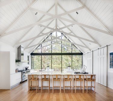 cathedral ceiling with floor to ceiling windows and beams in the kitchen