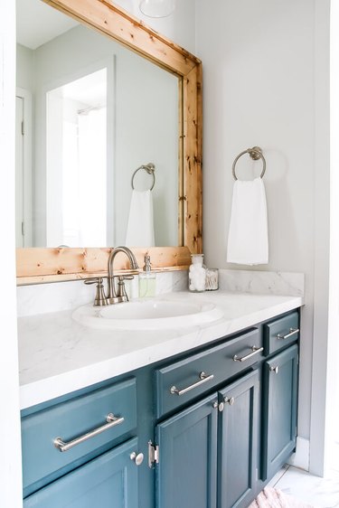 white bathroom with blue vanity and diy rustic decor wood frame mirro