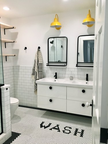 quirky bathroom floor tile idea in white bathroom with yellow wall sconces