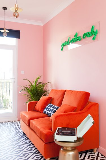 pink room living room with red sofa and green neon light