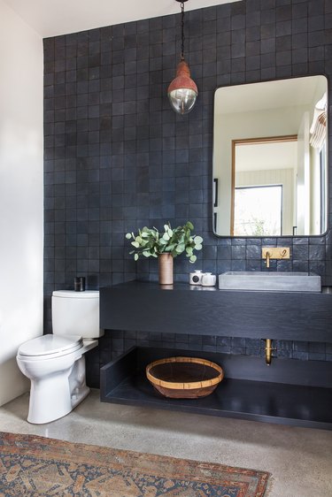 black floating bathroom vanity idea with textured black wall tile and hanging pendant