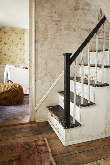 black and white rustic stair railing in hallway with wood floor and vintage rug
