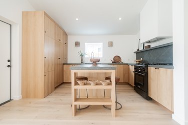 light hardwood floor colors in kitchen with light wood cabinets and black stone backsplash