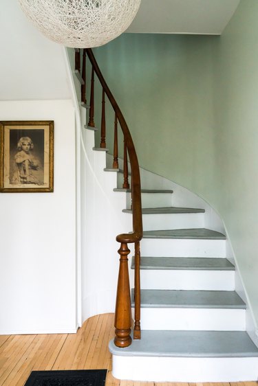 Rustic stair railing with white stair risers and wood railing in mint green entryway