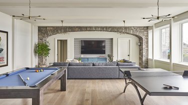 rustic man cave ideas with stone arch, pool table, and ping pong table