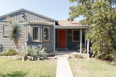 gray house with white and wood exterior window trim and red front door