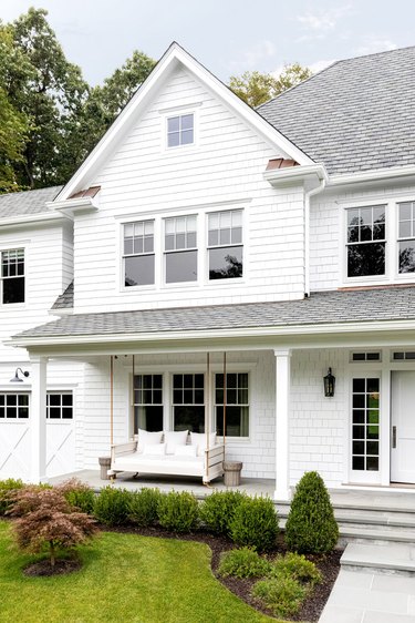 White clad house with white exterior window trim and porch swing